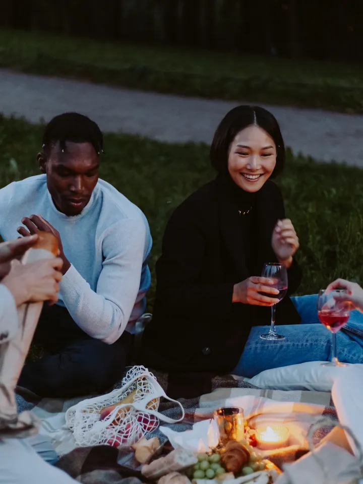 A couple sharing a drink on a picnic blanket at dusk — original