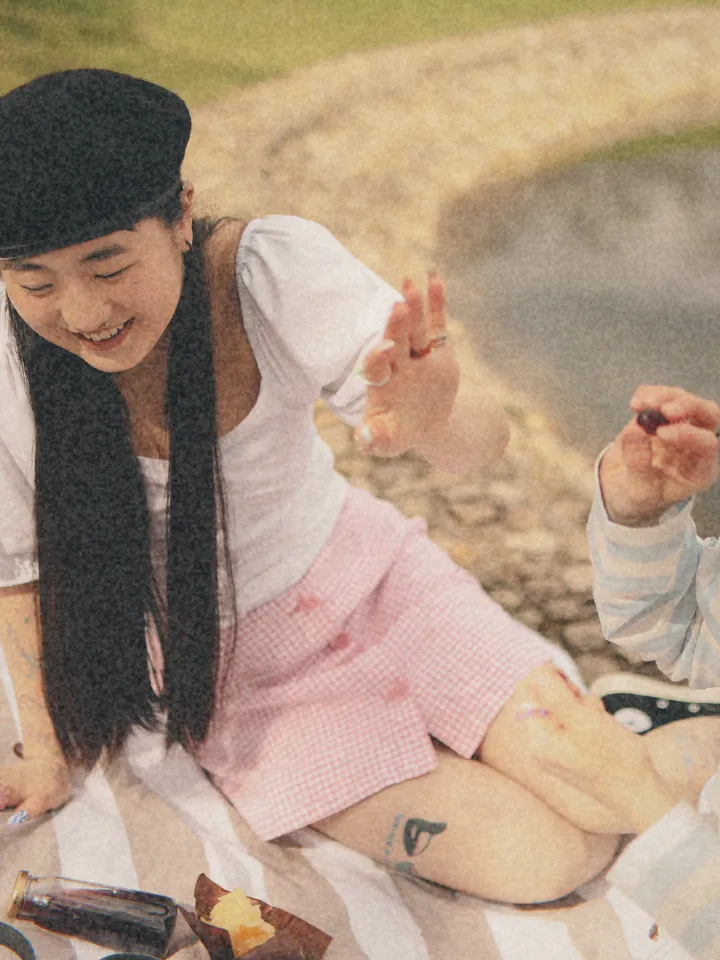 A woman in a pink skirt at a lakeside picnic — 1995 · Home Video