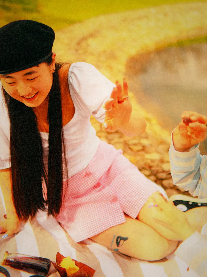 A woman in a pink skirt at a lakeside picnic — 1998 · Disposable Flash